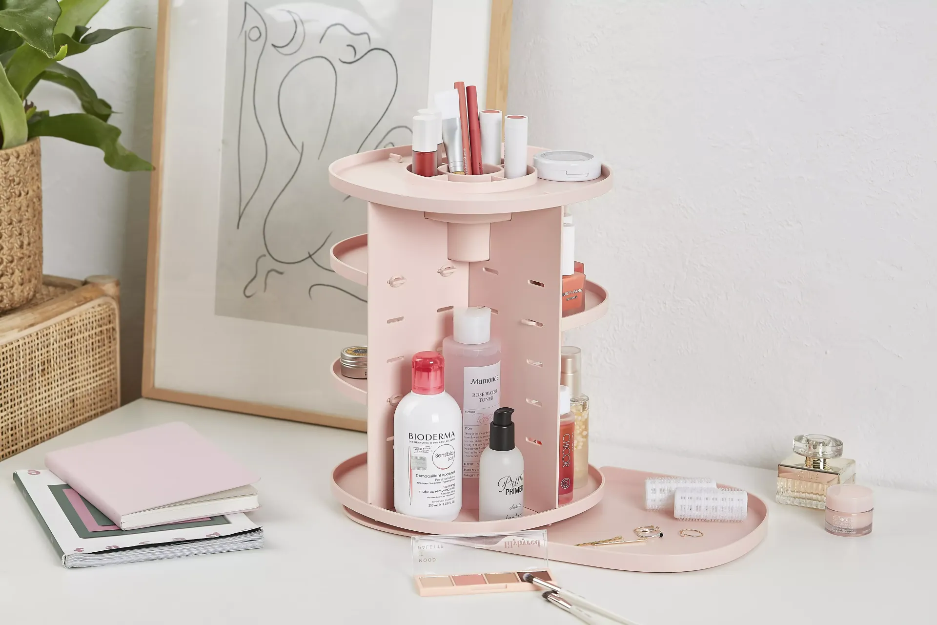 Un organizador de cosméticos rosa está sobre una mesa blanca.