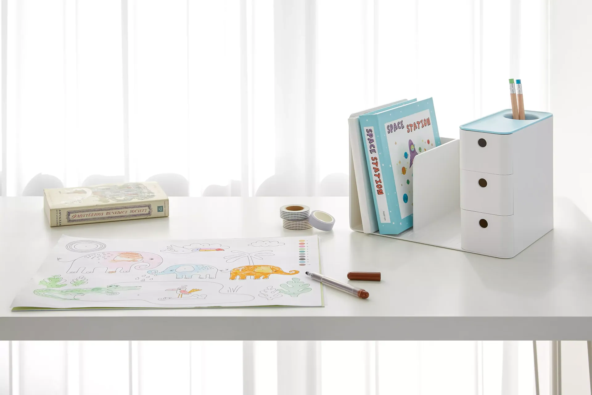 Uma mesa branca com um desenho e livros sobre ela num organizador da litem