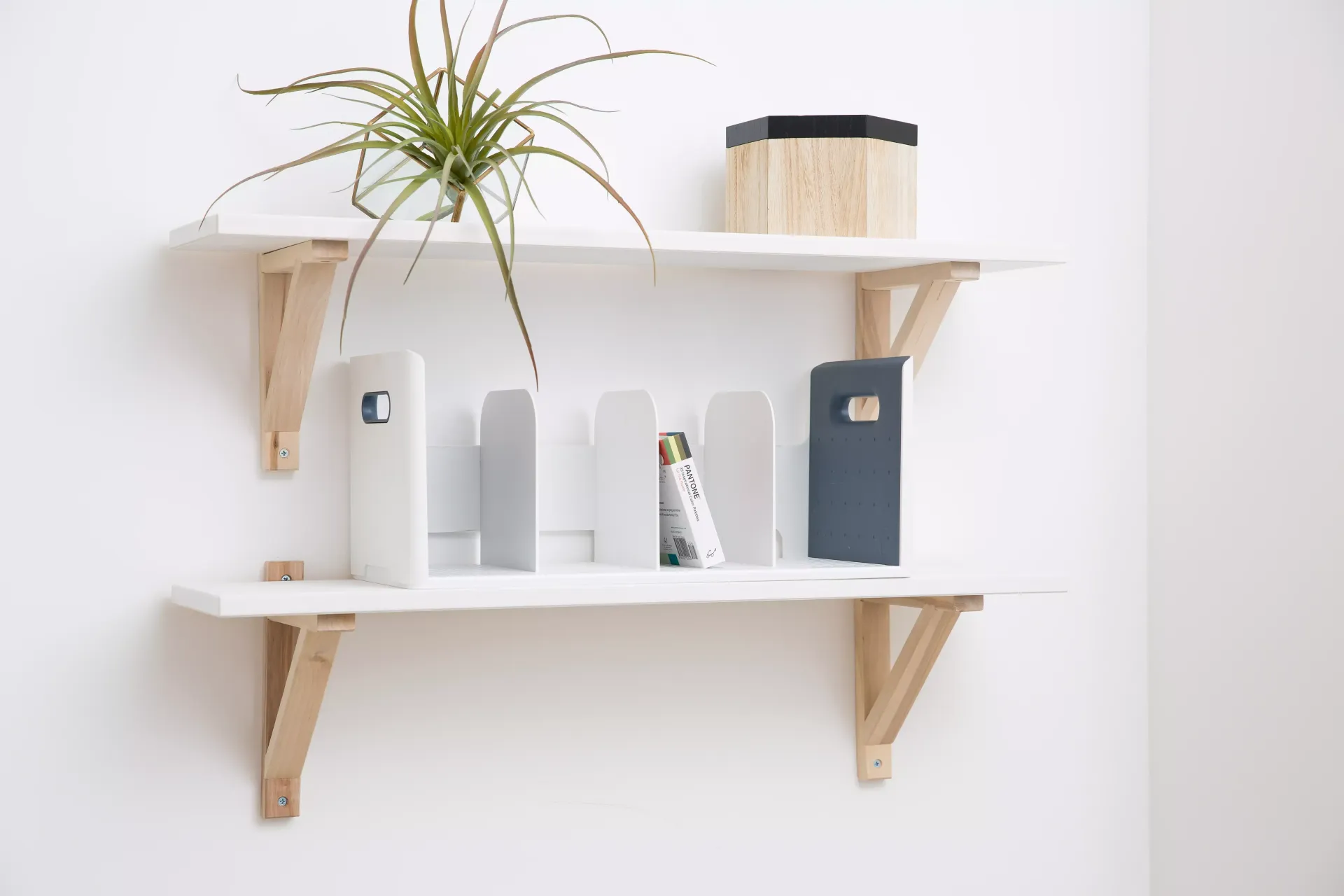 Una estantería blanca con soportes de madera y dos organizadores de libros encima.