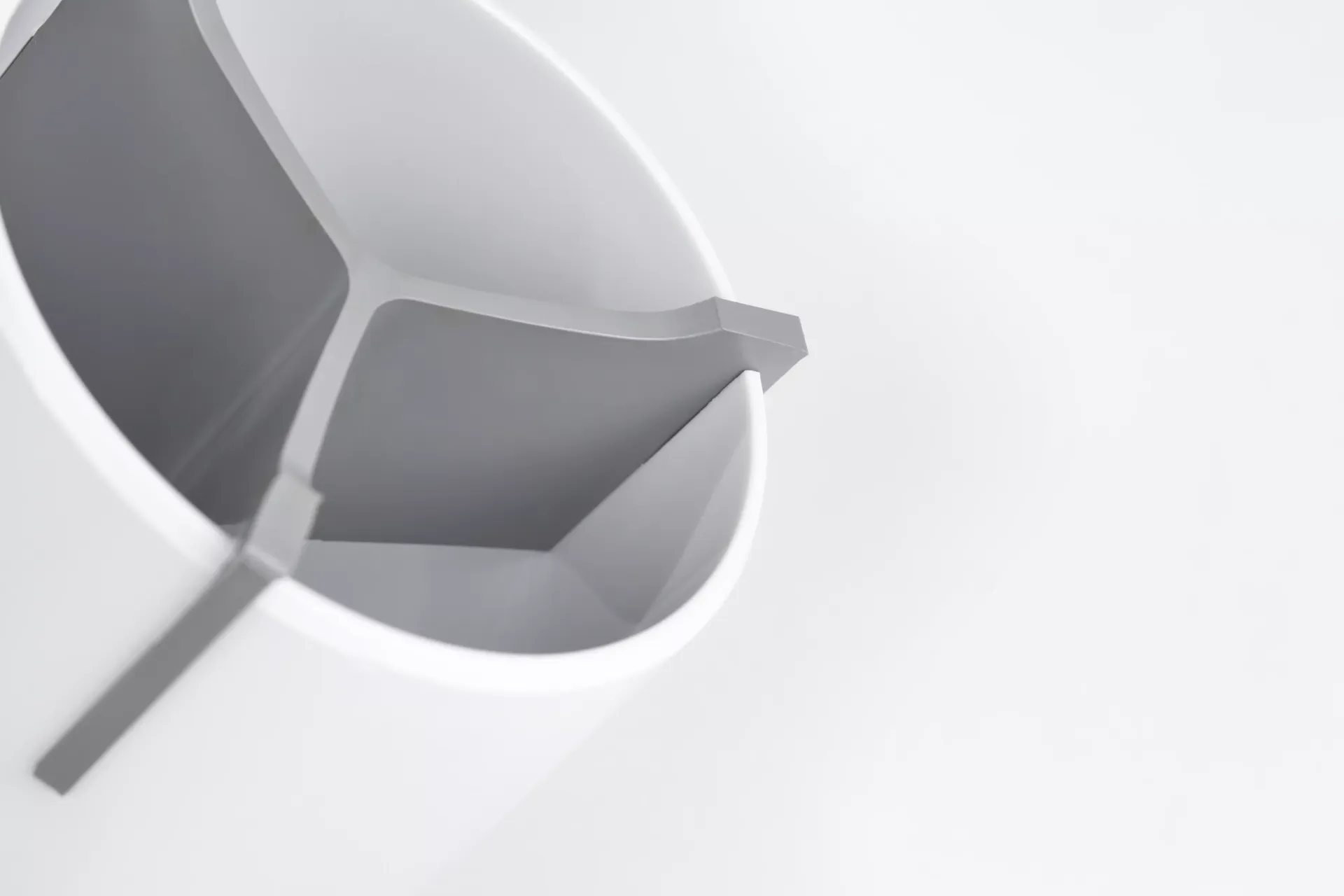 Primer plano de una taza blanca con asa sobre una superficie blanca.