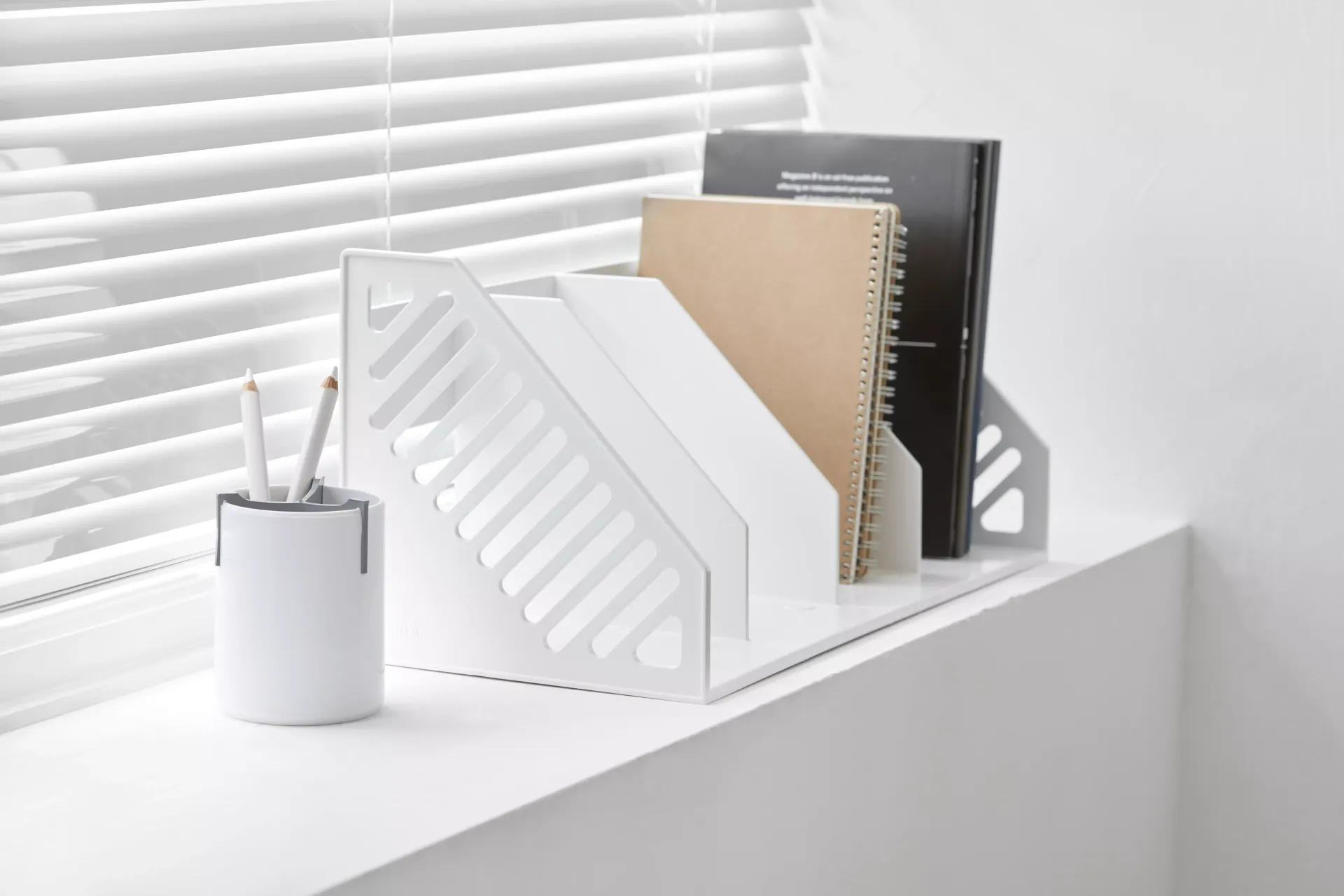 Una mesa blanca con un portalápices y un atril encima.