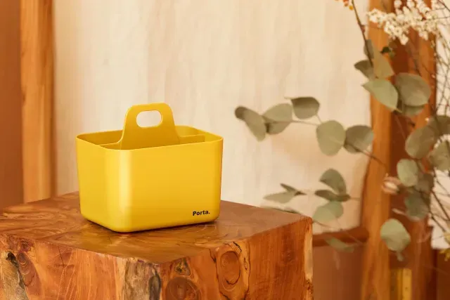 Un recipiente amarillo con asa está sobre un bloque de madera.