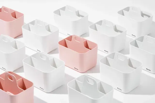 Un grupo de recipientes rosas y blancos están dispuestos uno encima del otro sobre una superficie blanca.