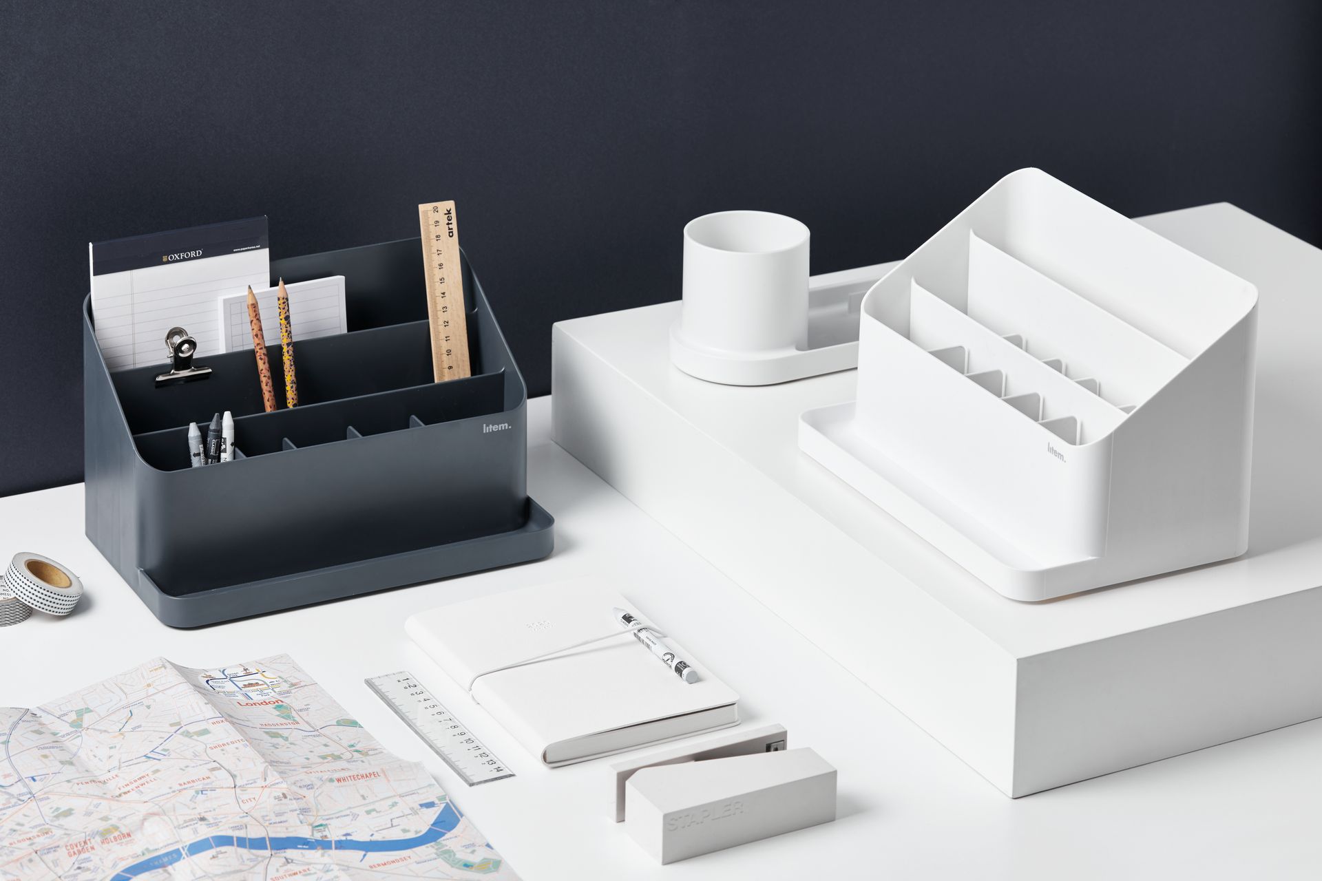 Una mesa con un montón de material de oficina encima y dos organizadores de Litem.