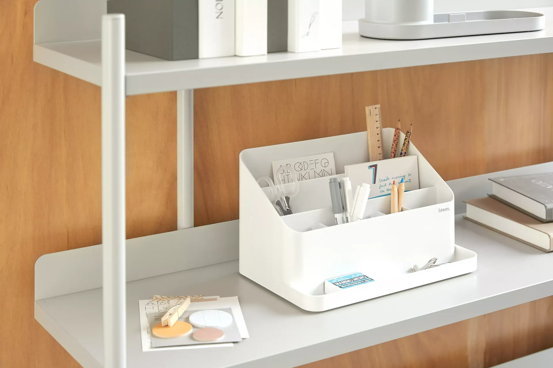 Un organizador de mesa blanco está encima de una estantería blanca.