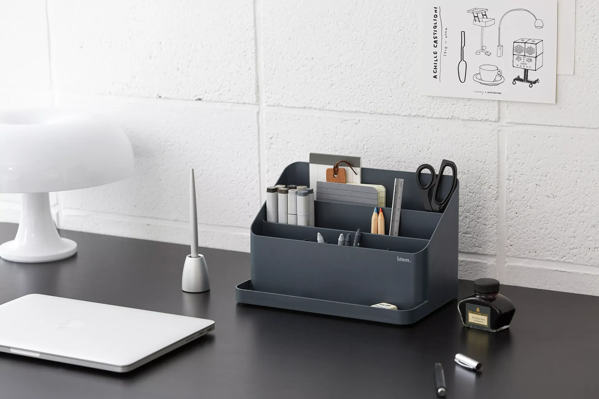 Una mesa con un organizador gris y un ordenador portátil encima.