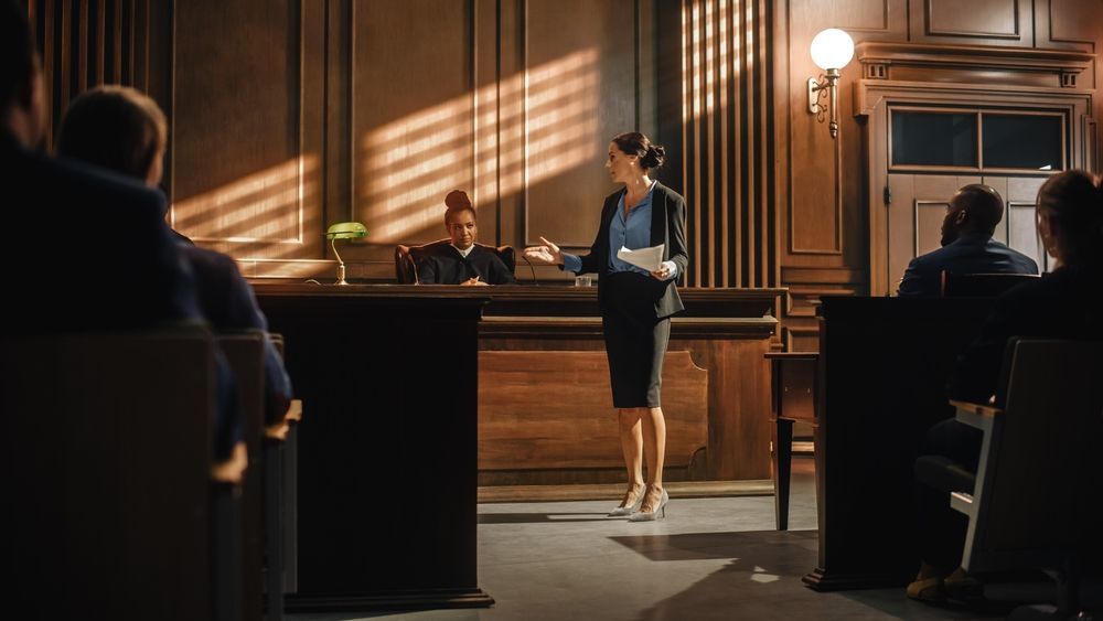 A woman is standing in front of a jury in a courtroom.