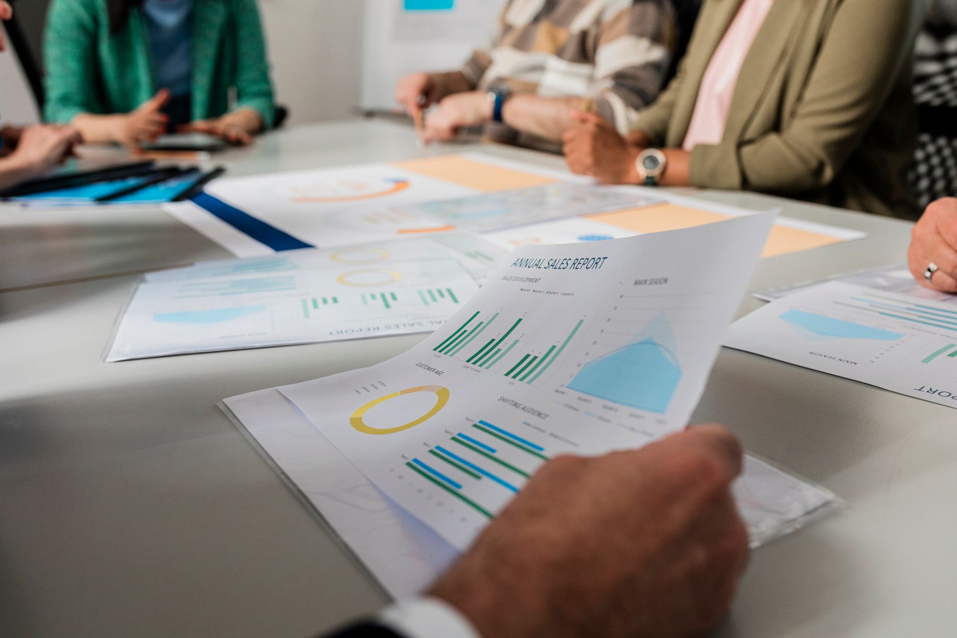 Close-up view of printed annual sales reports being examined during a business meeting.