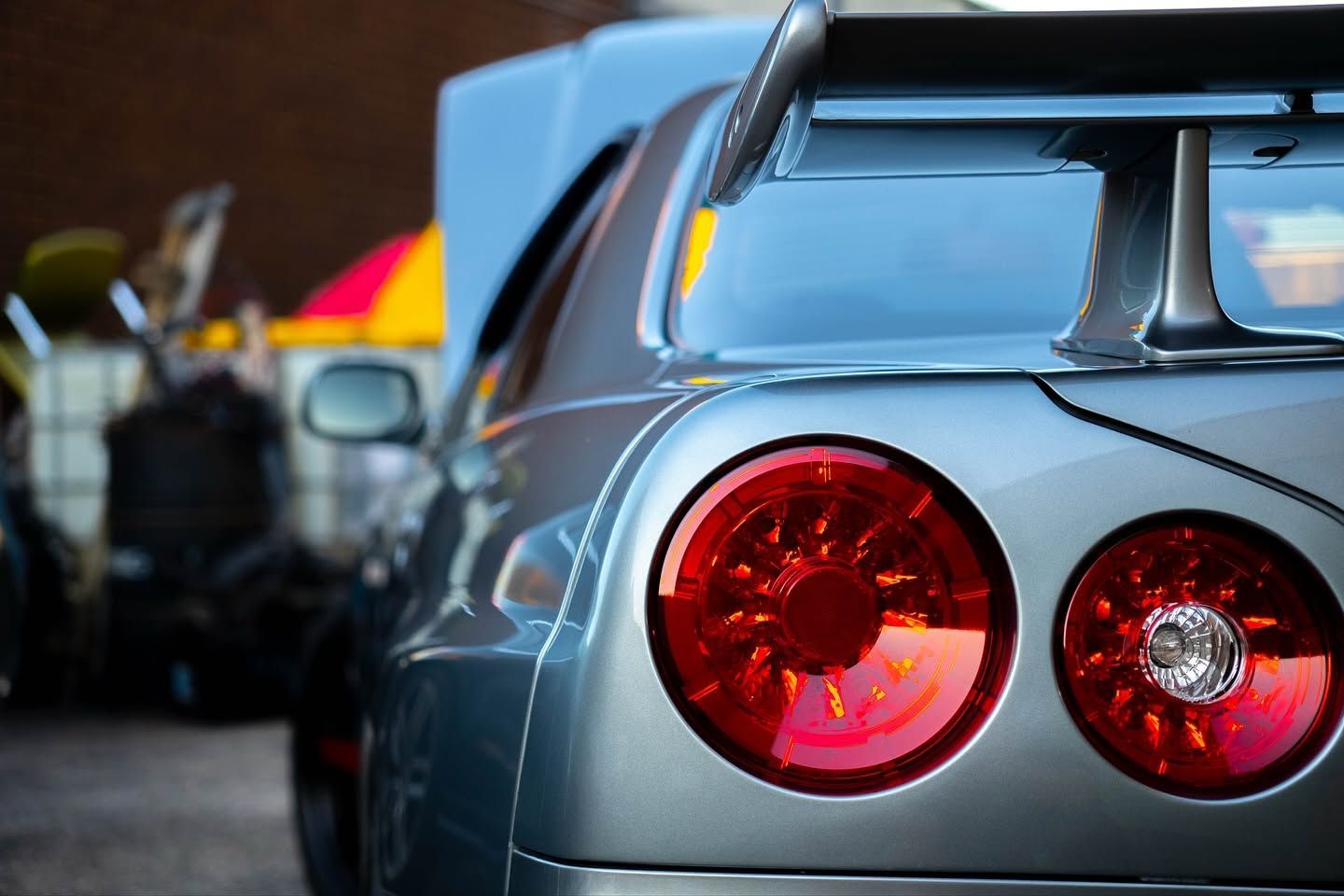 Silver sports car rear with red taillights at a car show