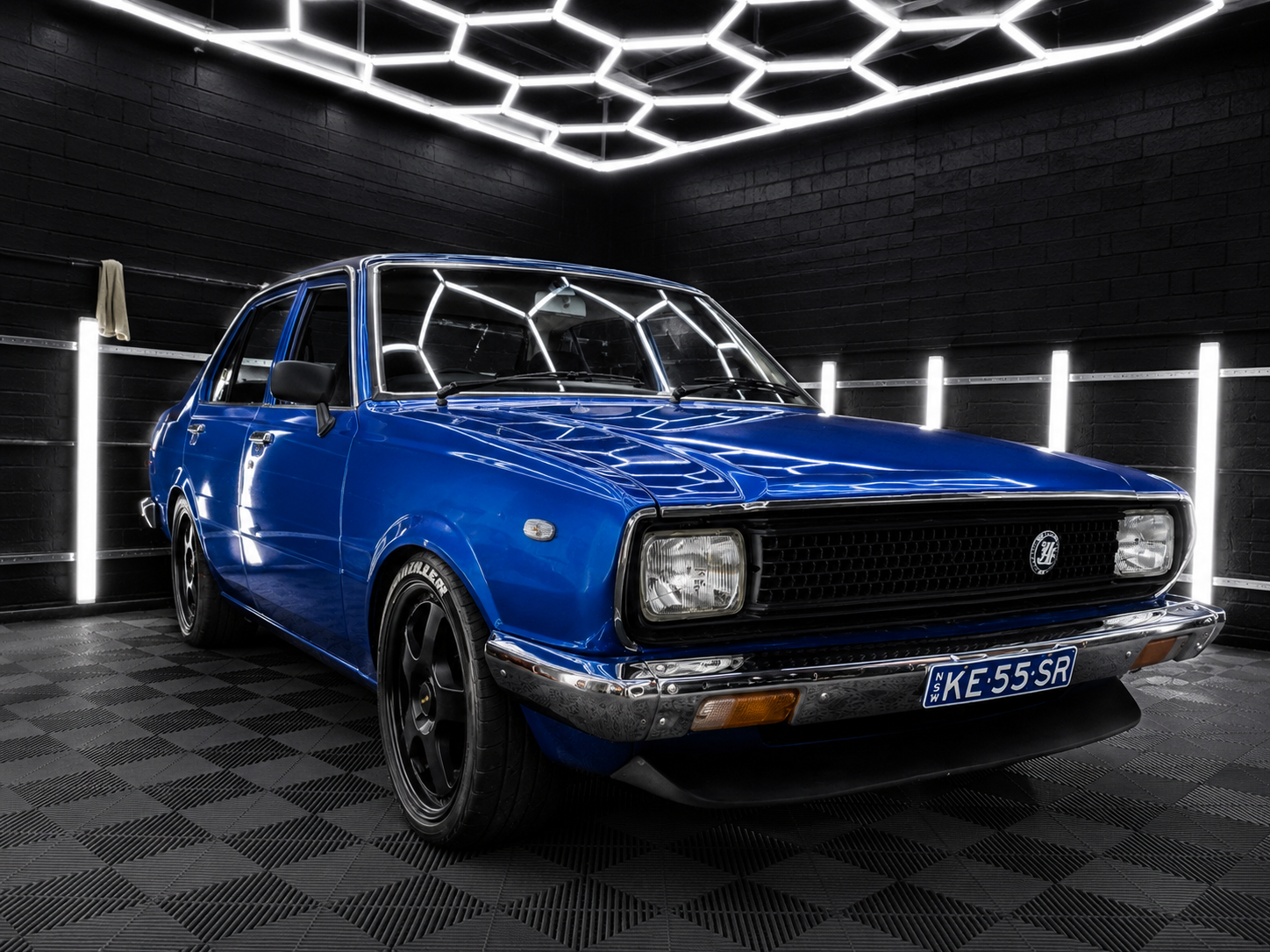 Blue classic Volkswagen coupe in a studio with a futuristic black-and-white geometric backdrop