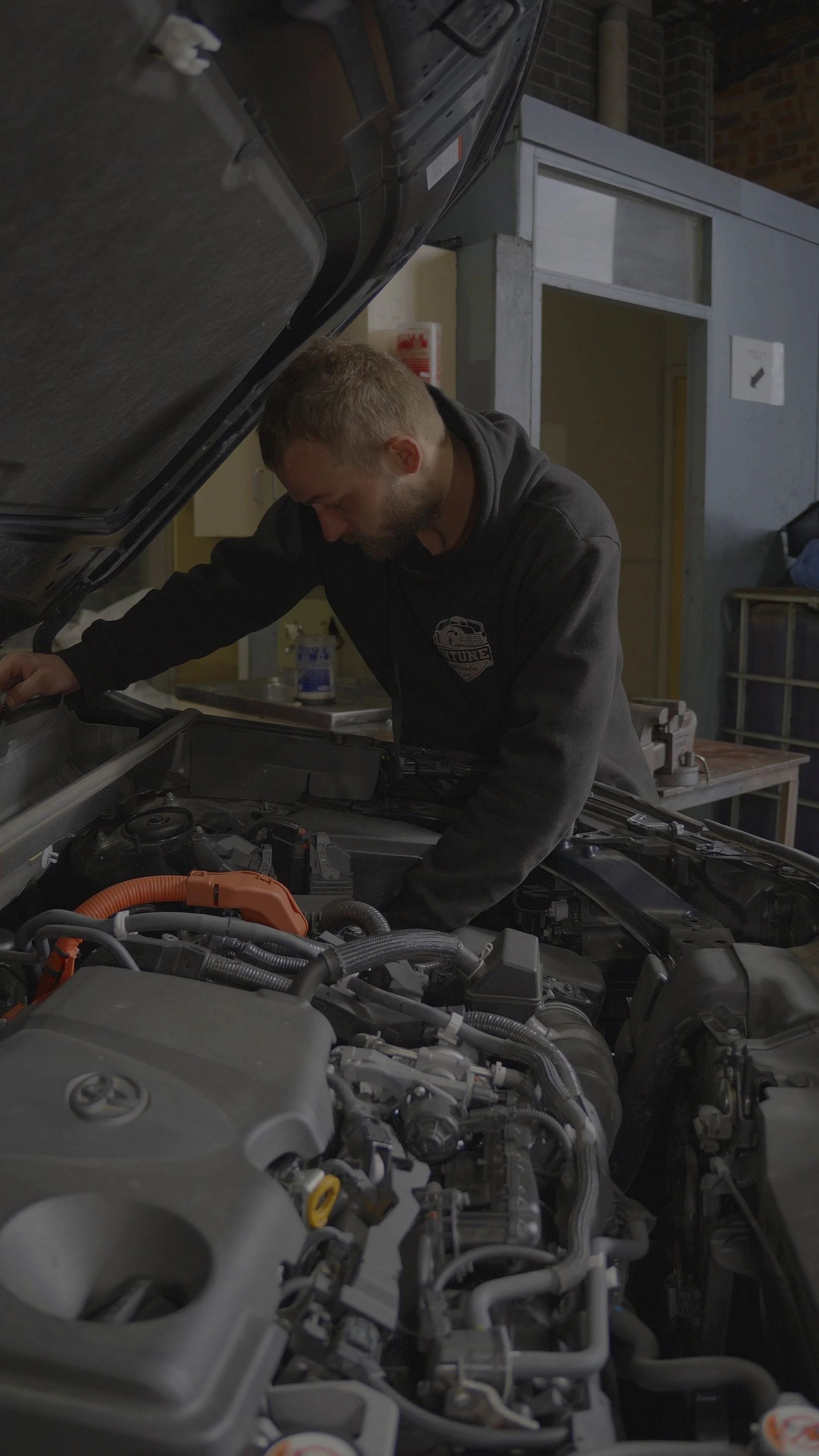Mechanic inspecting a car engine in a repair shop with the hood open