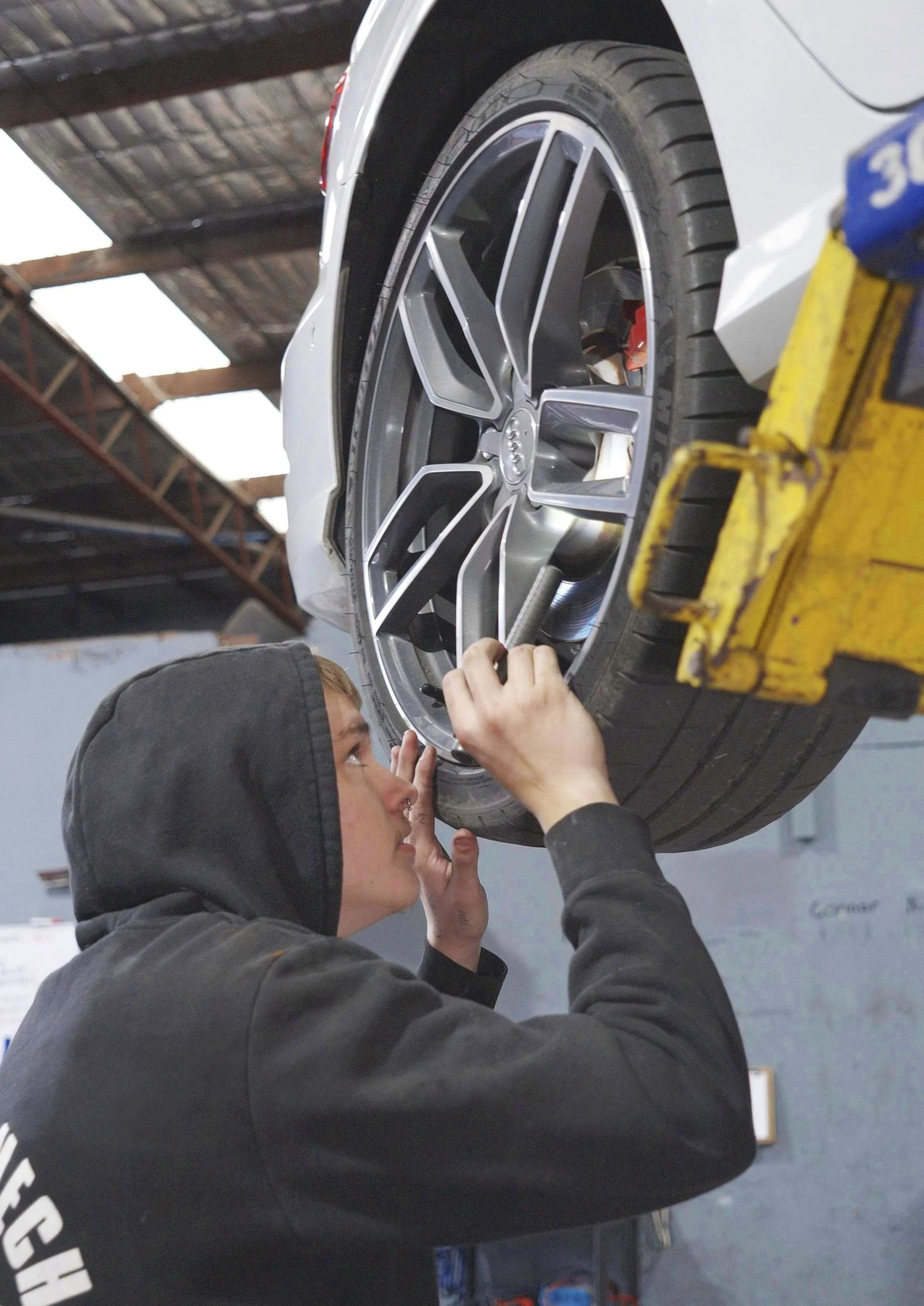 Person using a tool to work on a car wheel in a garage