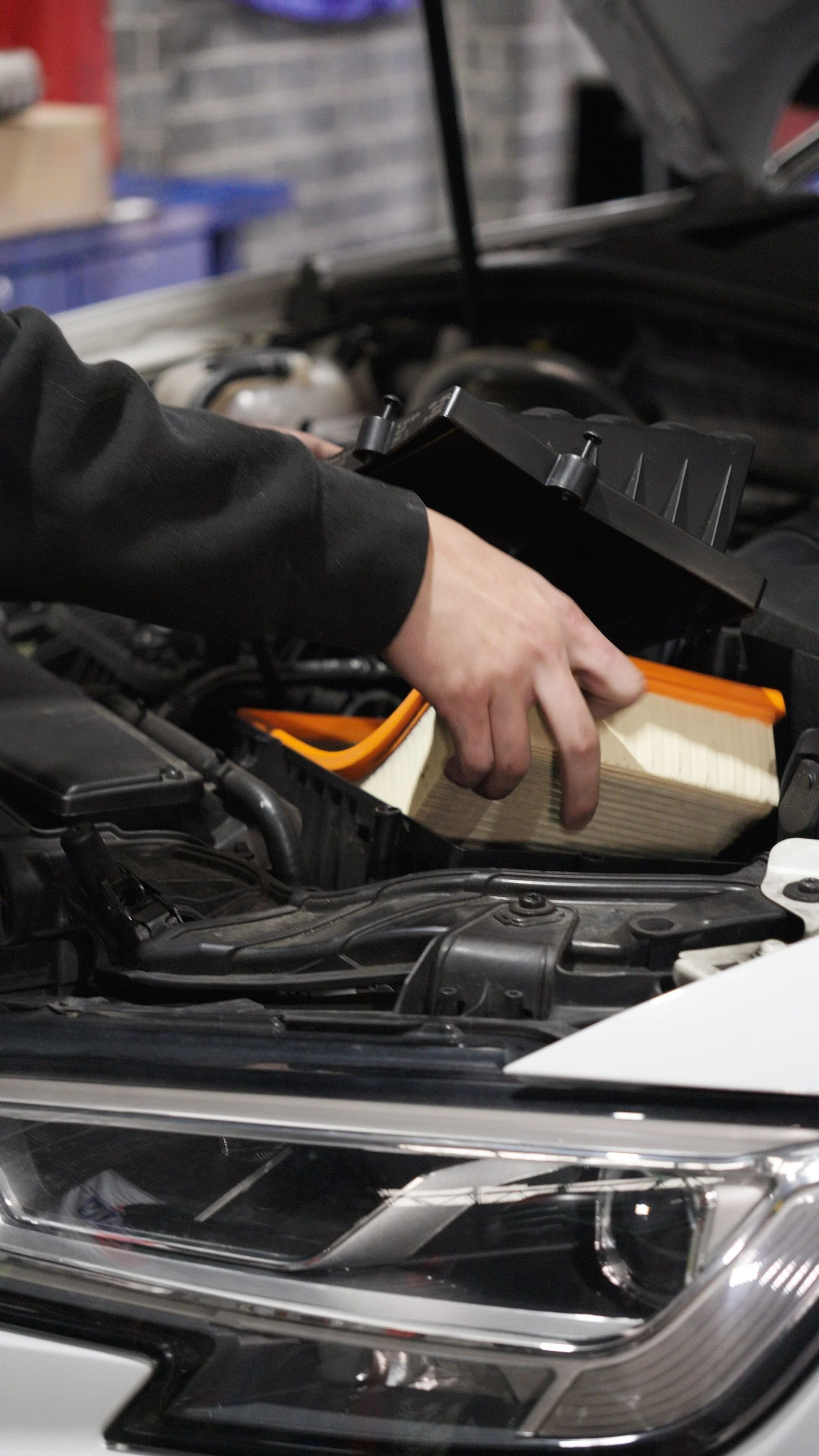 Hand cleaning a car air filter in the engine bay with the hood open