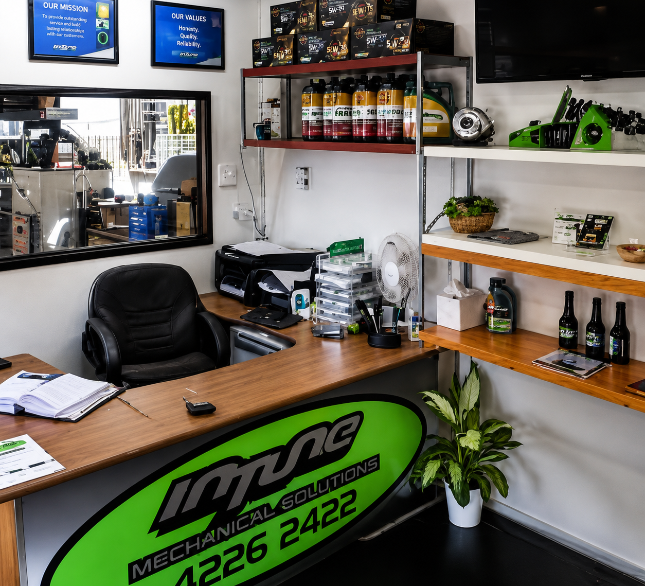 Indoor auto shop front desk with wood counter, green logo, shelves of bottles, and a black chair