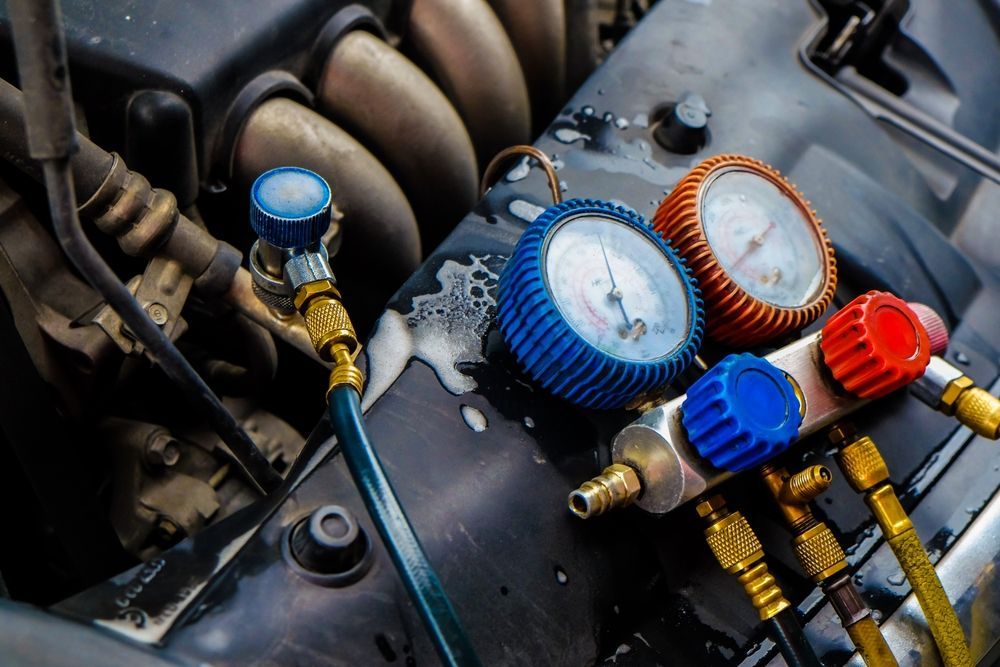 Auto engine bay with manifold gauge set and colored hoses attached for air conditioning service