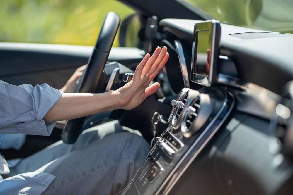 Driver’s hand raised to block a car touchscreen while driving
