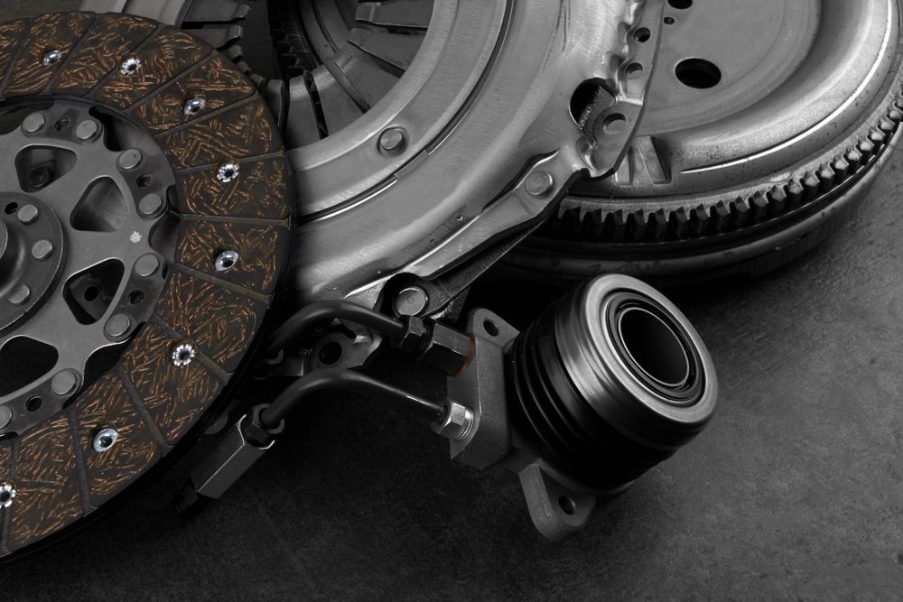 Assorted car clutch and transmission parts, including a rusted disc and metal components on a dark surface