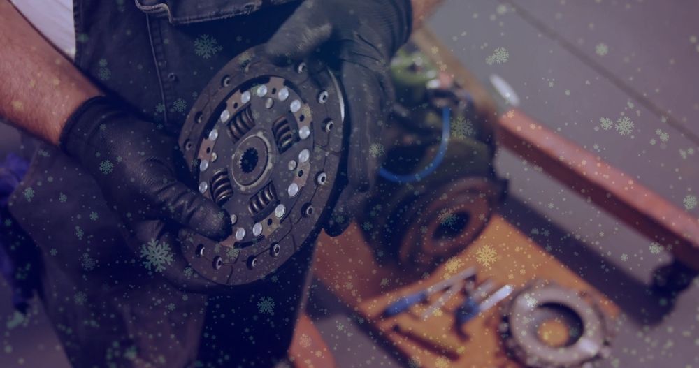 Gloved hands hold a metal grinder disc near tools on a workshop floor with a tile wall nearby