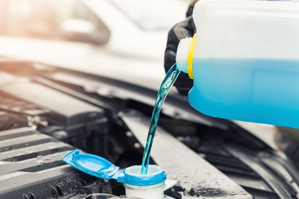 Hand using a wrench to repair a car engine in the front grille area