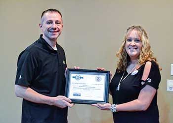 A man and a woman are holding a framed certificate.