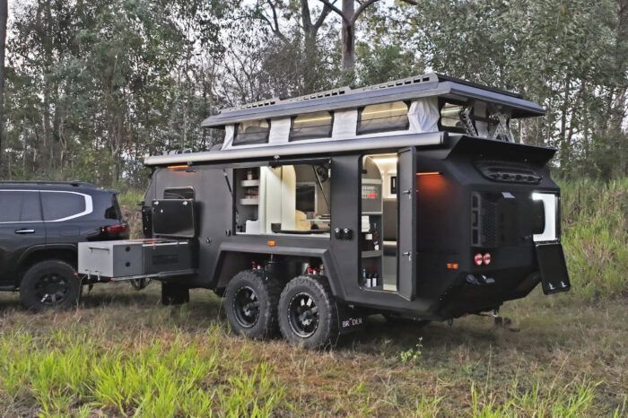 A black trailer is being towed by a black suv in a field.