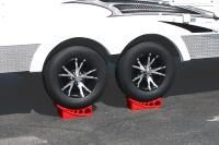 The wheels of a trailer are on red ramps.