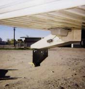 A close up of the underside of a trailer in a parking lot.