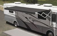 A large rv with an awning is parked on the side of the road.