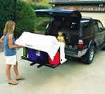 A woman is loading a cooler into the back of a suv.
