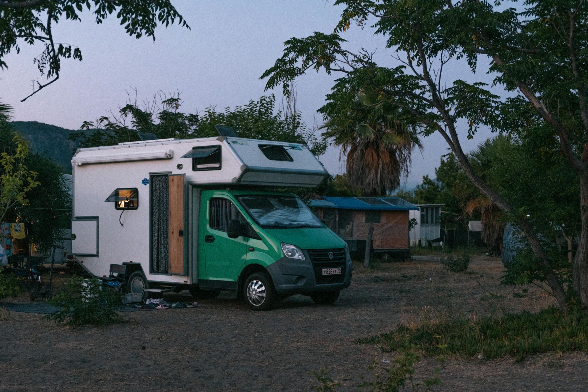 A green and white camper van is parked in a dirt lot
