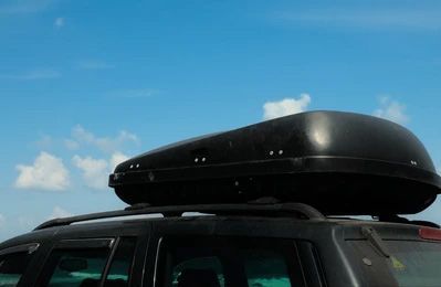 A black roof box is sitting on top of a car.