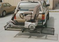 A mobility scooter is attached to the back of a truck.