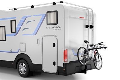 A white rv with two bikes attached to the back of it.