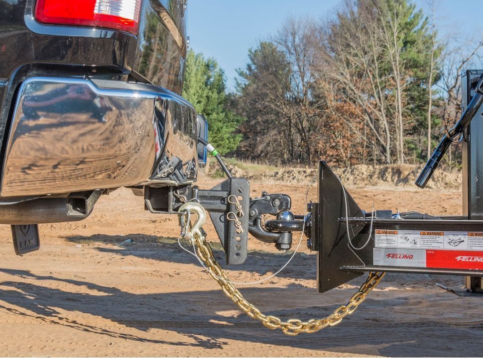 A truck is towing a trailer on a dirt road Littleton colorado Trailer Hitch Inspection Guidelines