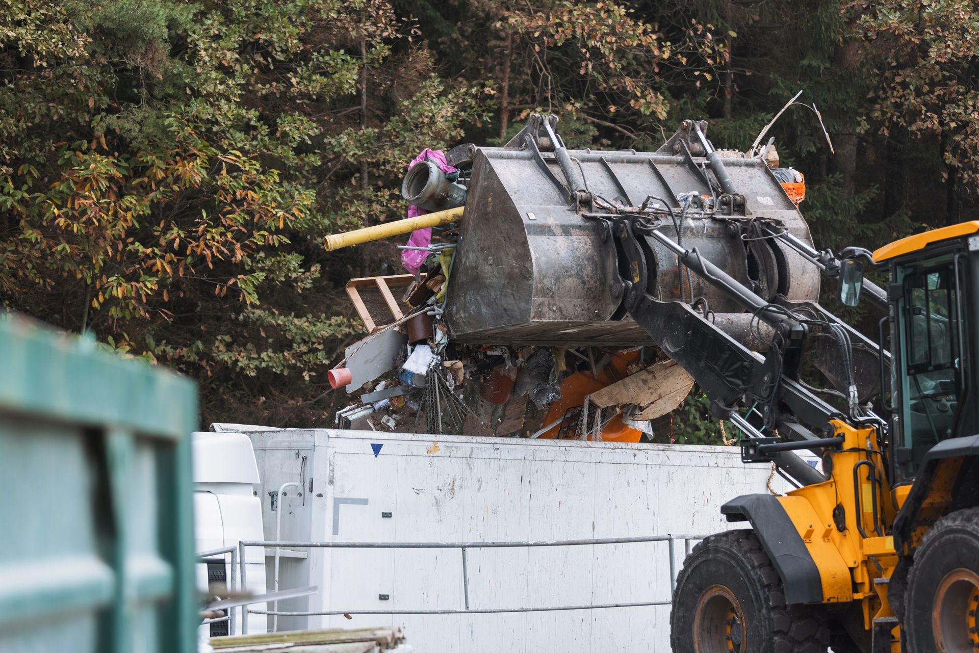 Forklift loading cargo into a semi-truck trailer, outdoor setting.