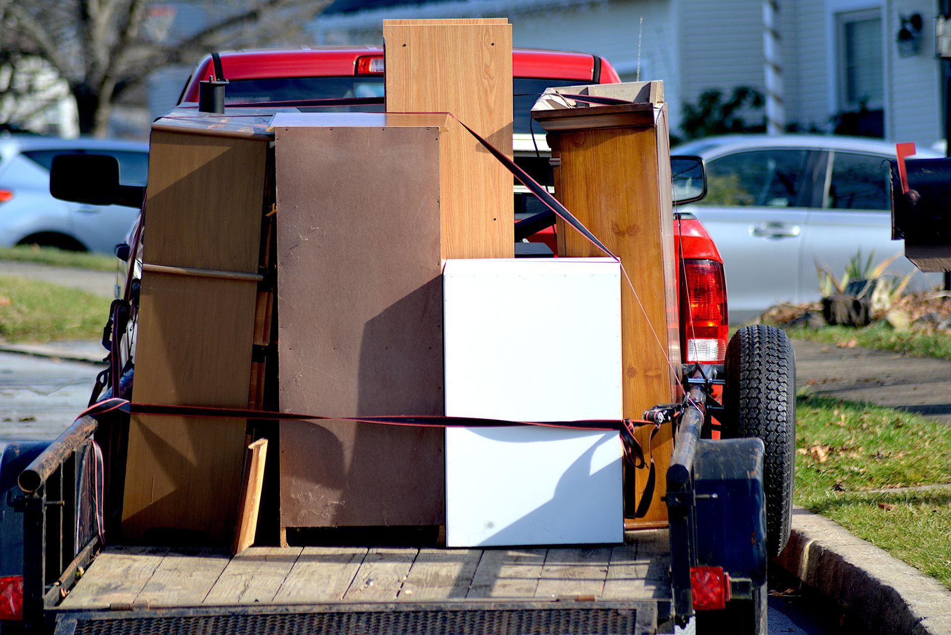 Truck bed loaded with furniture pieces, secured with straps.