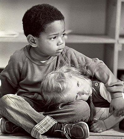 A black and white photo of two children sitting on the floor