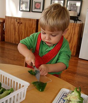 a little boy cutting vegetables in a Montessori classroom