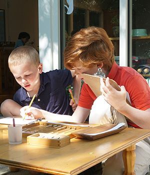 Two boys are sitting at a table looking at a clipboard