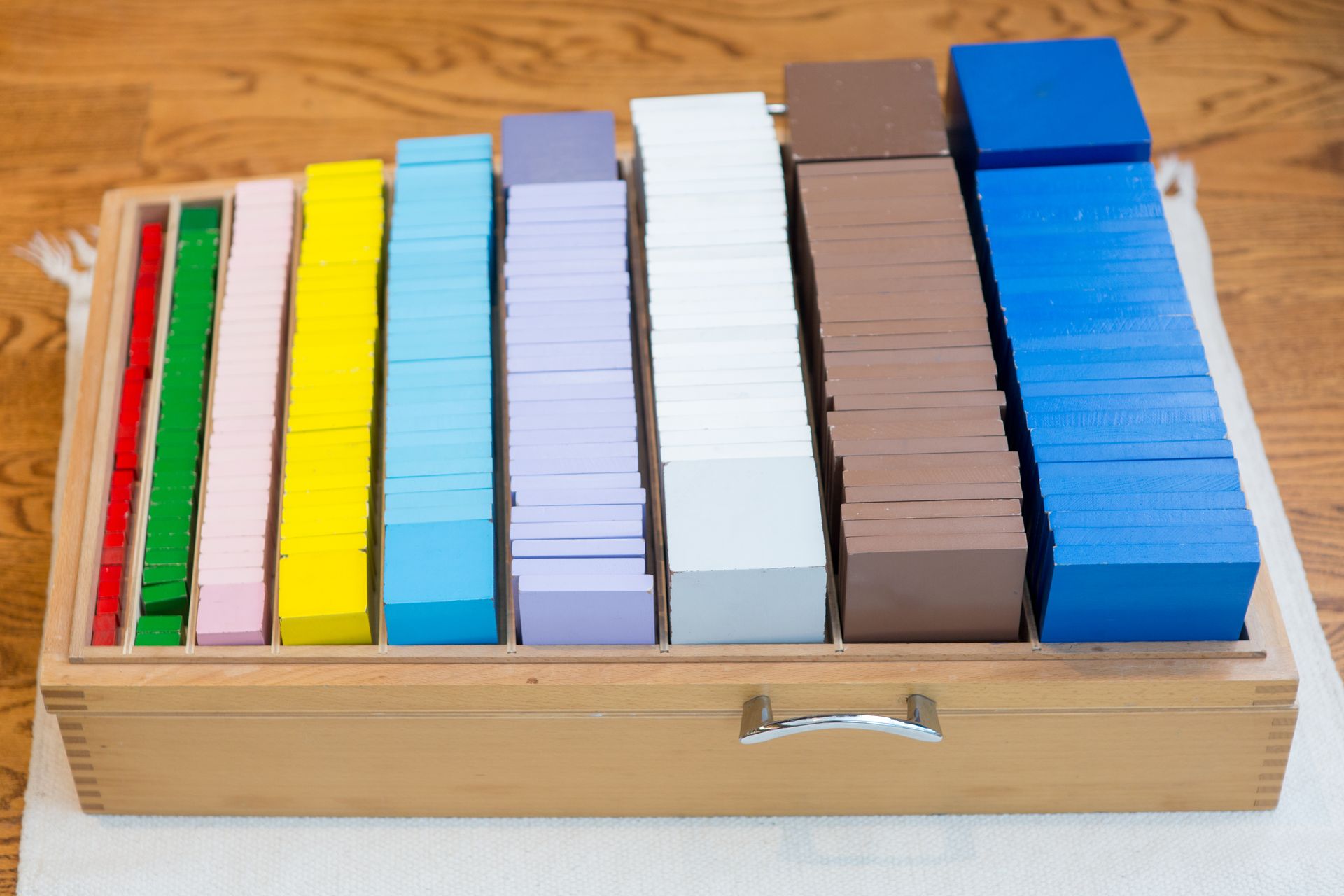 A wooden box filled with a variety of colorful wooden blocks.
