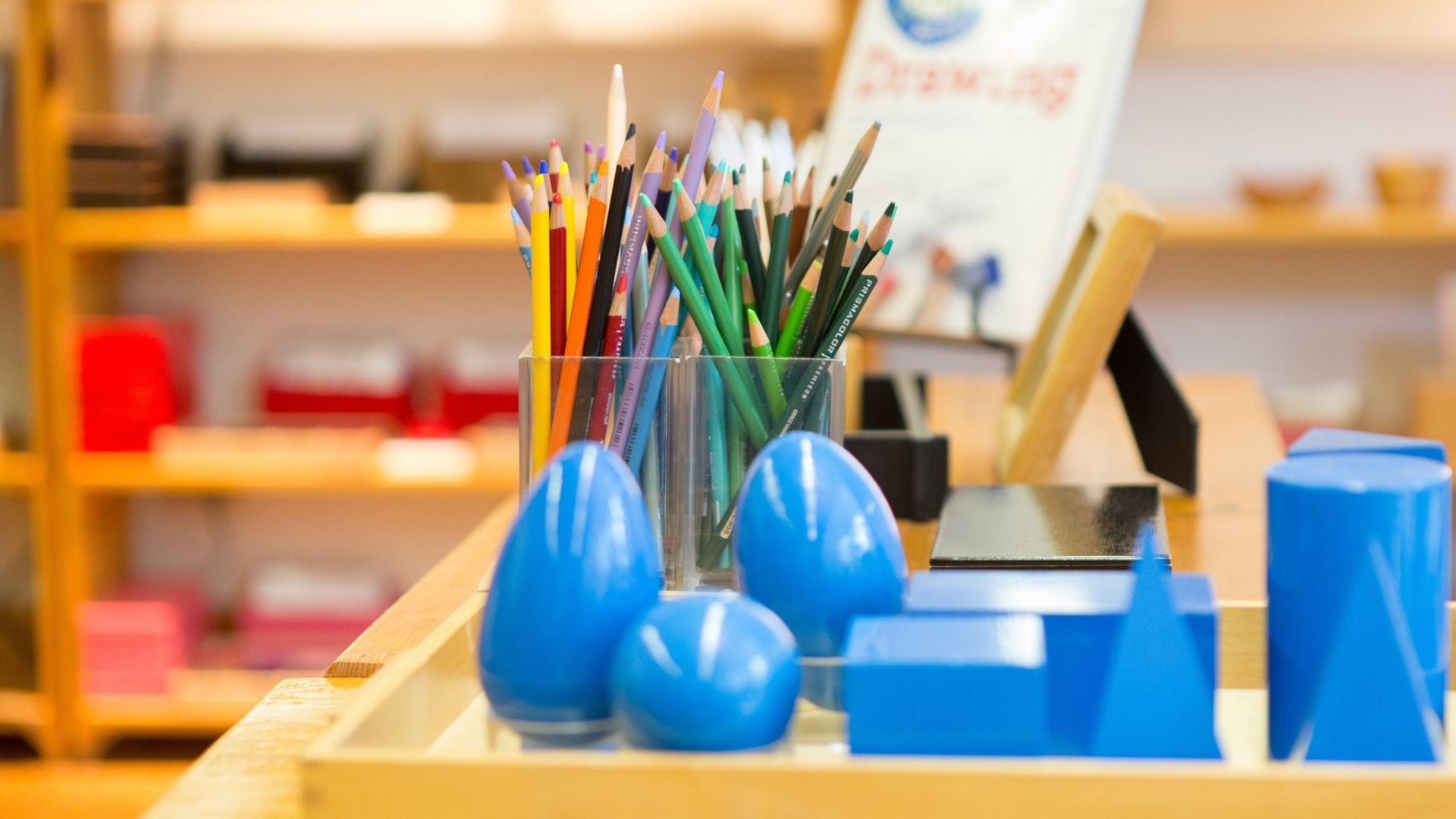 A tray of blue toys and pencils on a table.