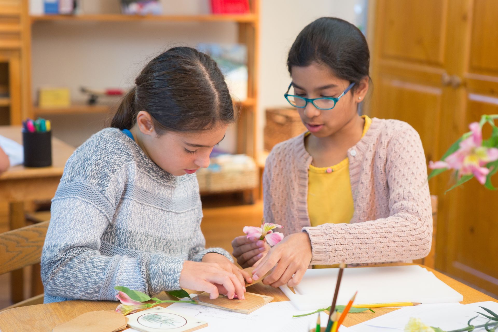 Montessori children are sitting at a table working on a project.