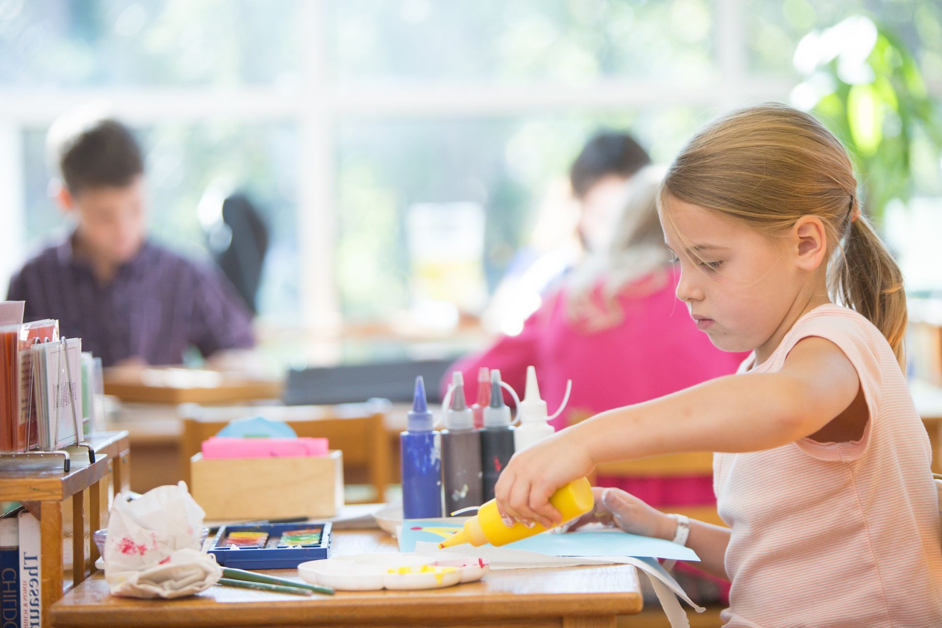 Montessori child is sitting at a desk in a classroom working with materials