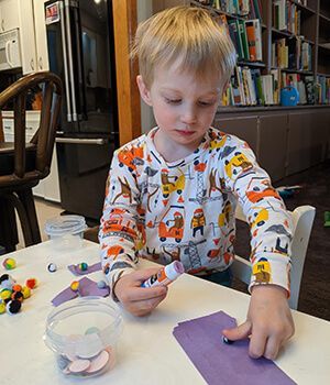 A boy in pijama workgin on a table with paper