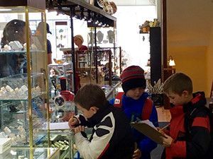 A group of young boys are looking at a display case in a store.