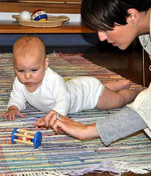 A woman is playing with a baby on the floor