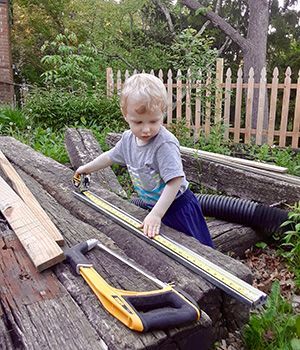 A boy playing in a backyard with wood logs 