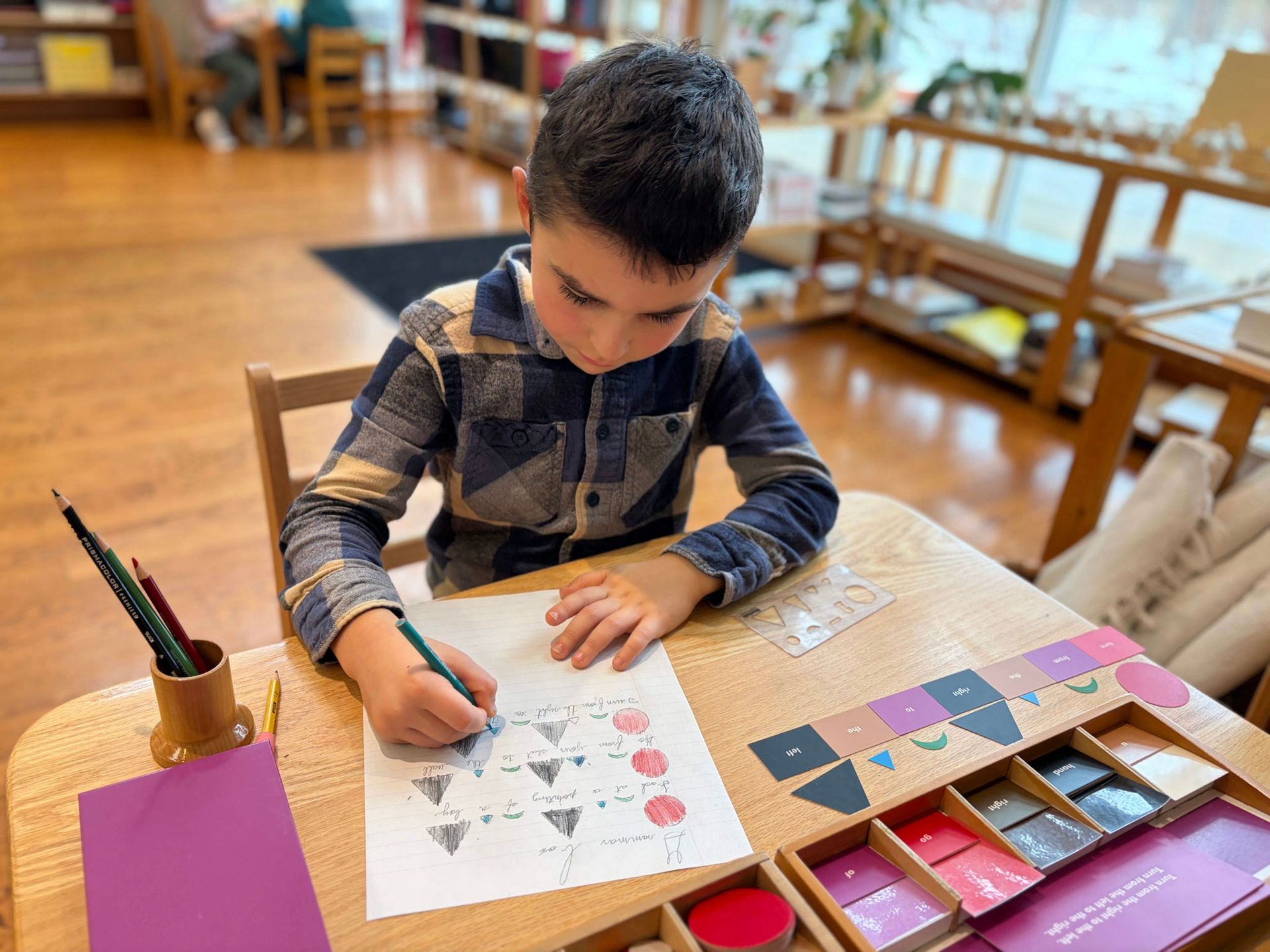 An elementary aged boy works with a Montessori grammar box to label parts of speech
