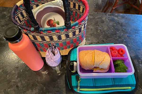 A lunch box with a sandwich and a water bottle on a table.