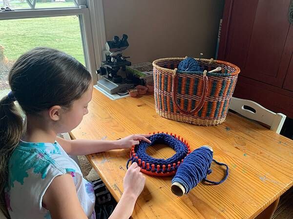 Montessori child is sitting at a table knitting